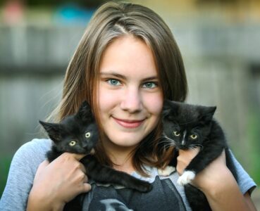 Jeune fille et deux chatons noirs
